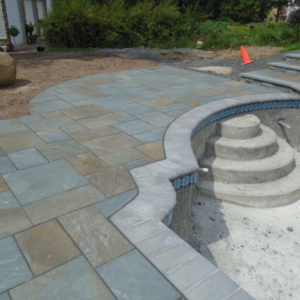 This Pennsylvania bluestone patio design follows the unique shape of the pool.