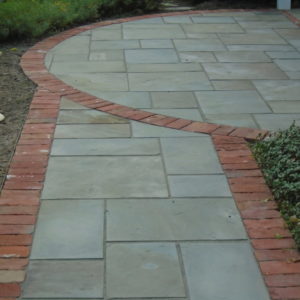 A Pennsylvania bluestone walkway edged in natural brick is one of many combinations that can add visual interest.