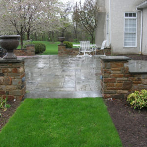 This natural stone sitting wall and piers capped with bluestone complements the large patio area.