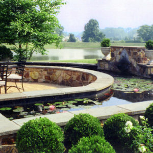 This large raised Koi pond with aquatic plants arcs around the patio, which allows everyone a great view of the pond.