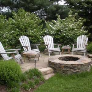 This relaxing seating area is enhanced by a natural stone firepit and creates a warm gathering place for all seasons.