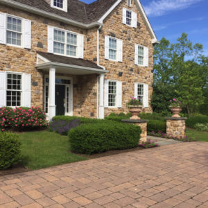 This formal landscape design with paver driveway and stone piers creates a beautiful entrance to the home.