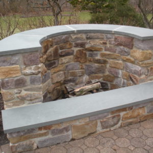 This unique shaped natural stone firepit capped with bluestone is one of many styles that can be constructed.