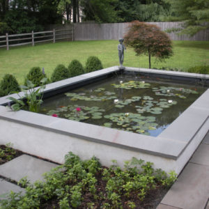 Capped with bluestone this raised formal masonry pond offers a place to sit and view the pond.