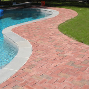 This herringbone patterned clay brick complements the bluestone coping of the pool.
