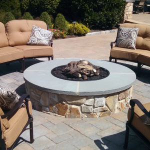 This natural stone gas firepit offers a relaxing environment to socialize in the evening.